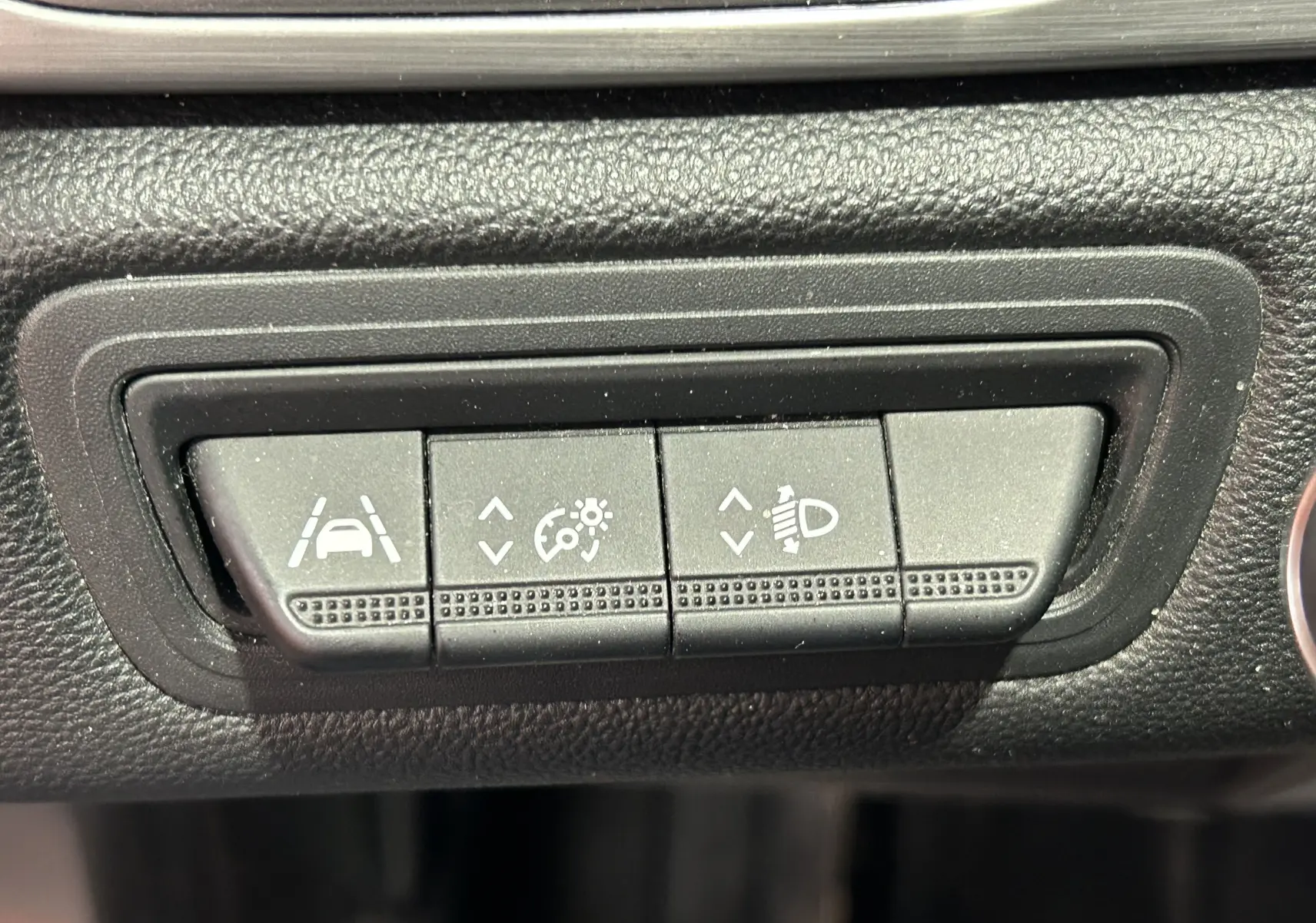 Gros plan sur les boutons de réglage d'assistance à la conduite et des phares dans un Renault Captur gris de 2020.