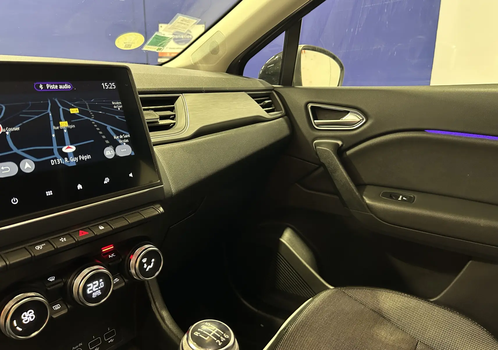Intérieur du Renault Captur gris, vue côté passager avec écran GPS allumé et détails de la console centrale.