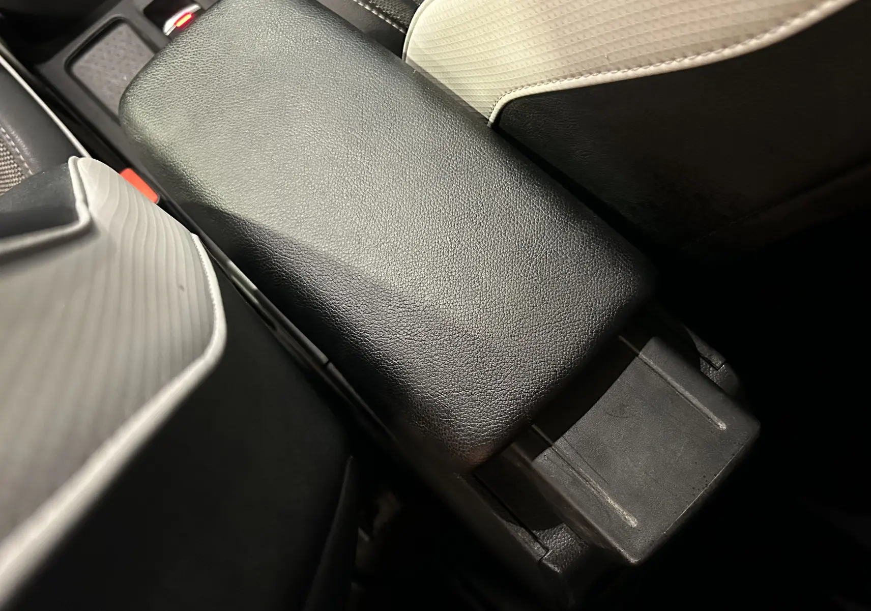 Gros plan sur l'accoudoir central en cuir noir et les sièges bicolores gris clair et noir du Renault Captur 2020.