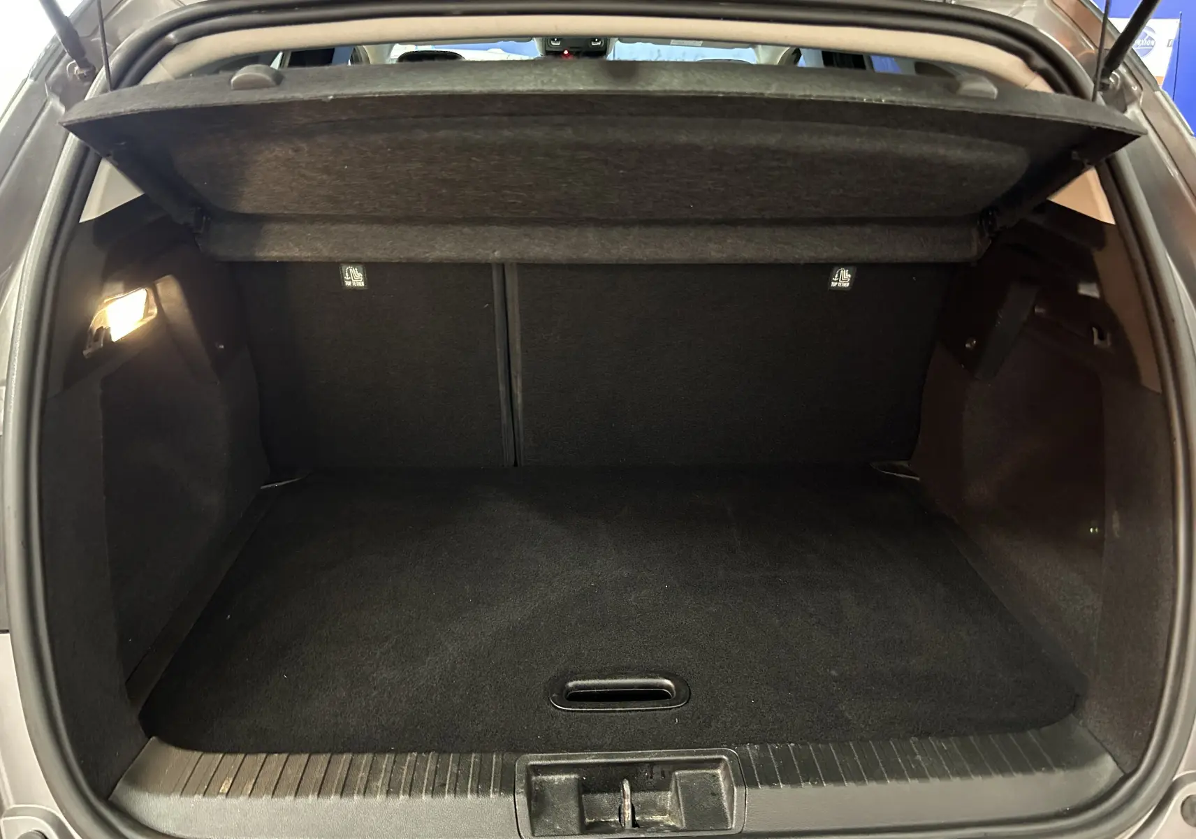 Coffre ouvert du Renault Captur gris vu de l'arrière, montrant un espace de chargement propre et éclairé.