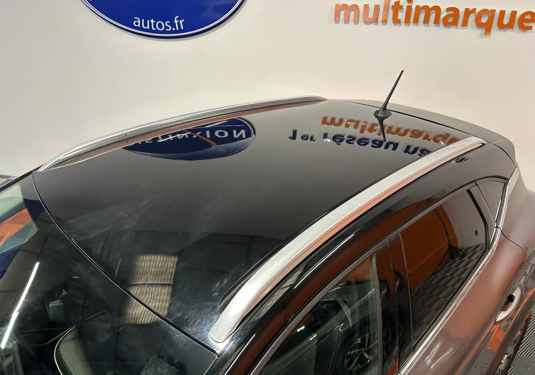 Vue plongeante sur le toit noir brillant et la carrosserie grise du Renault Captur 2020, avec barres de toit argentées visibles.