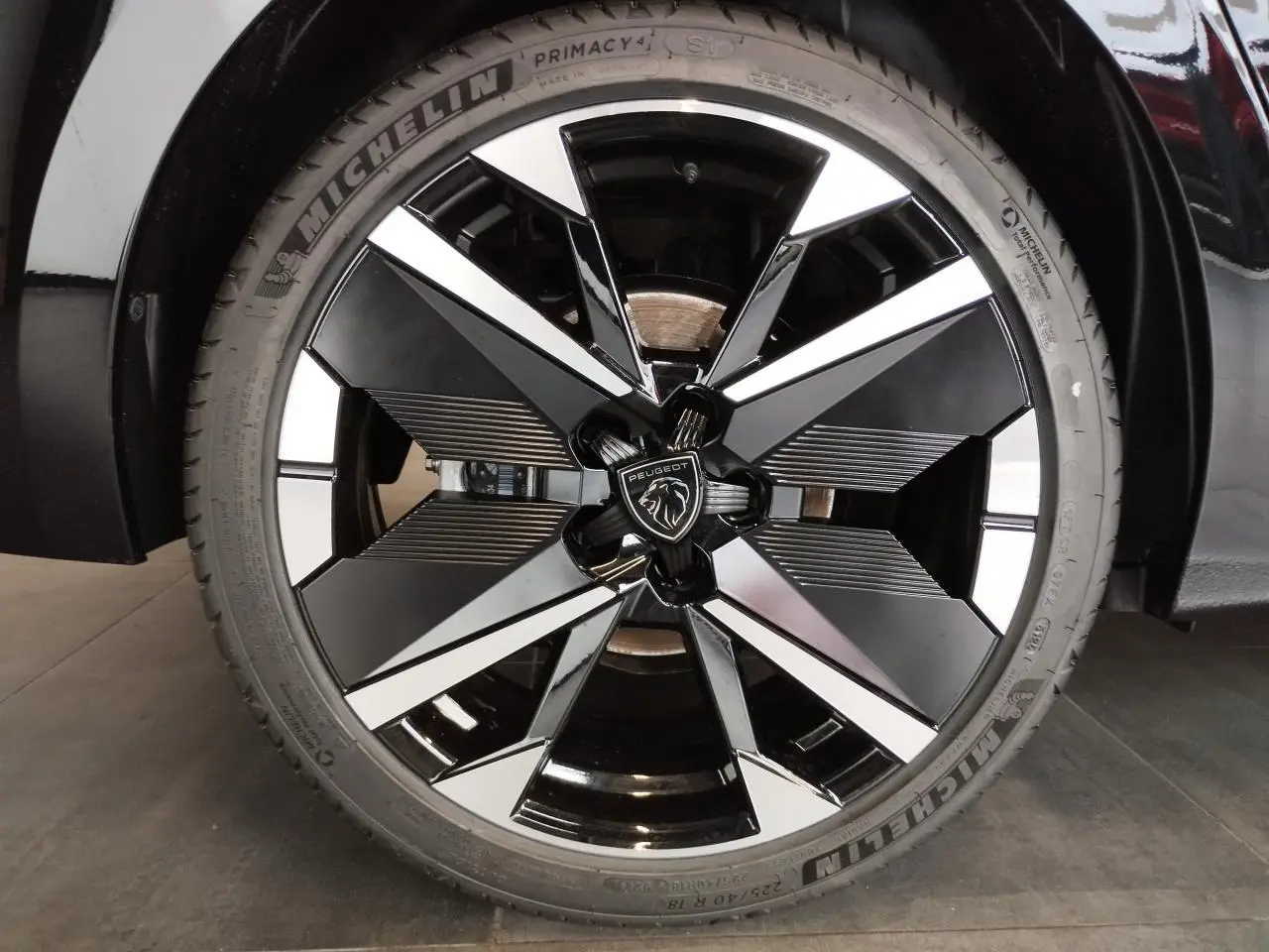 Gros plan sur la jante alliage 18 pouces bi-tons noir et argent avec logo Peugeot au centre sur Peugeot 308 noir métallisé.