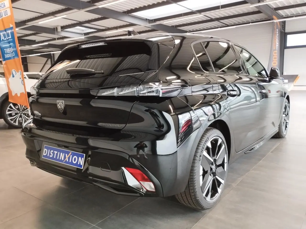 Peugeot 308 Hybrid noir métallisé vue 3/4 arrière droit, jantes alliage bi-ton et feux arrière LED griffés.