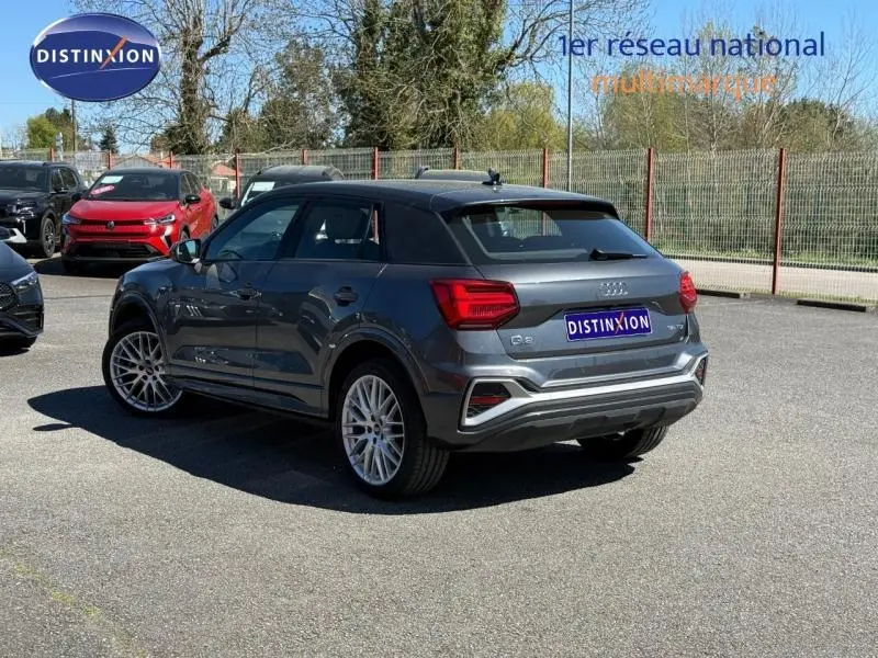 Audi Q2 35 TDI S line gris Daytona nacré, vue 3/4 arrière droit, avec jantes alliage et feux LED distinctifs.