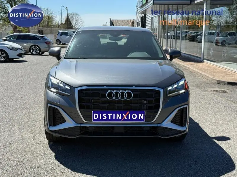 Audi Q2 35 TDI S line gris Daytona nacré, vue de face mettant en valeur la calandre noire et les phares LED.