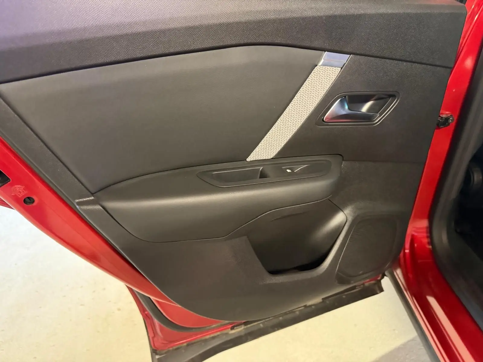 Vue rapprochée de la porte arrière gauche rouge d'une Citroën C4 X 2021, avec garniture noire et insert gris texturé.