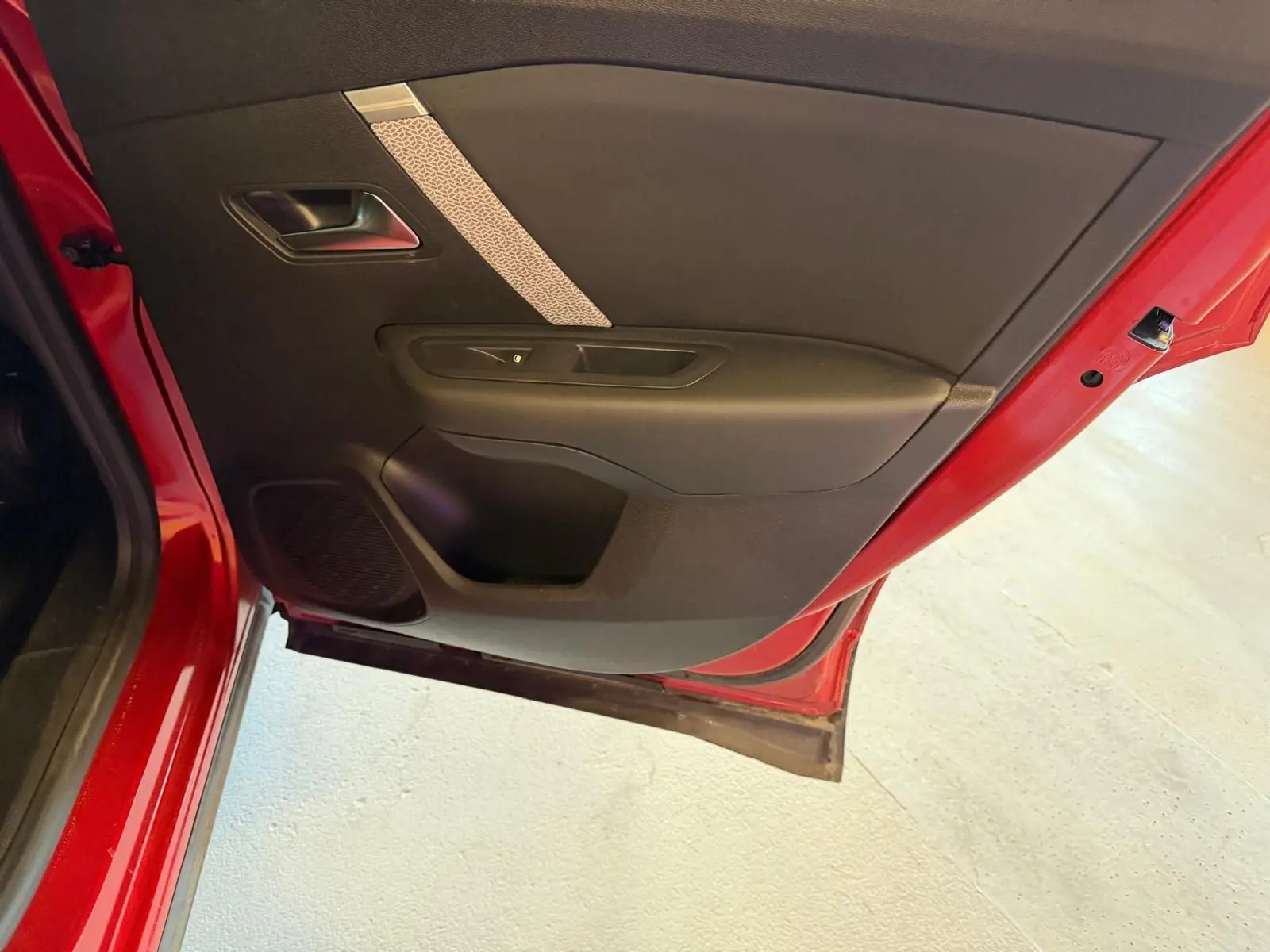 Vue rapprochée de la porte arrière gauche rouge du Citroën C4 X avec garniture intérieure noire et bande décorative claire.