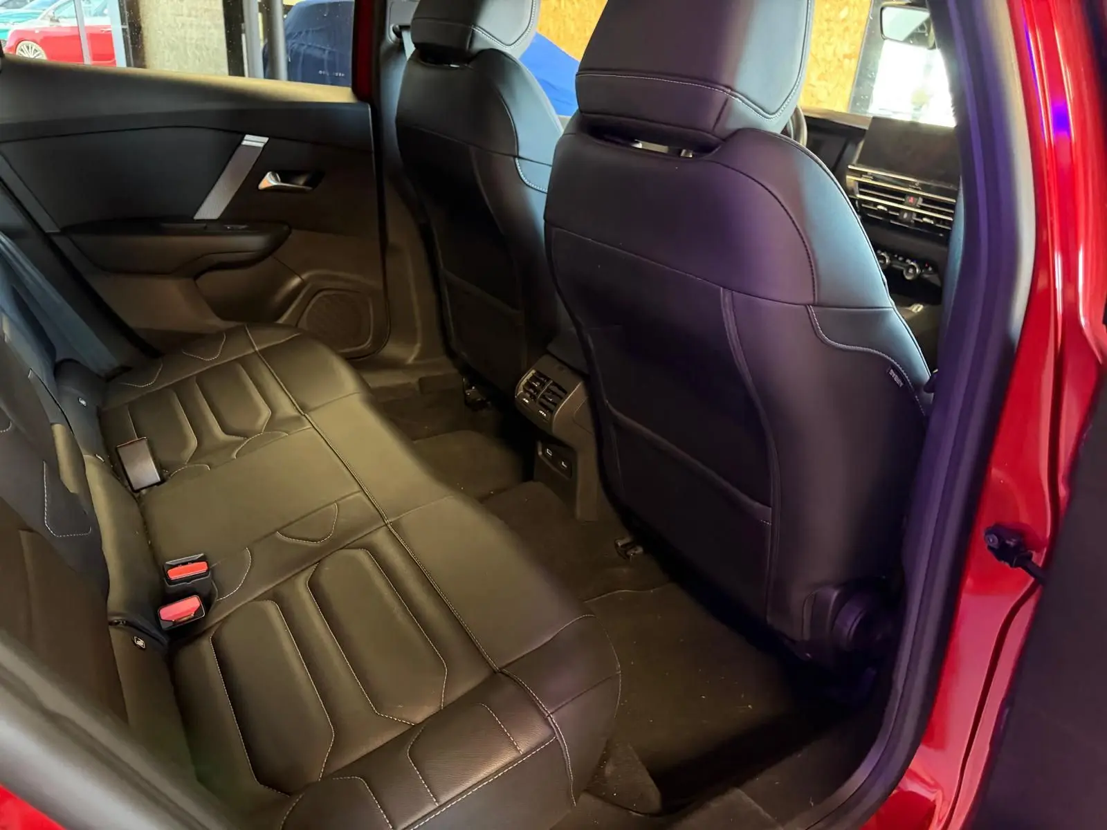 Vue intérieure côté gauche des sièges arrière en cuir noir du Citroën C4 X rouge, avec ventilation arrière visible.