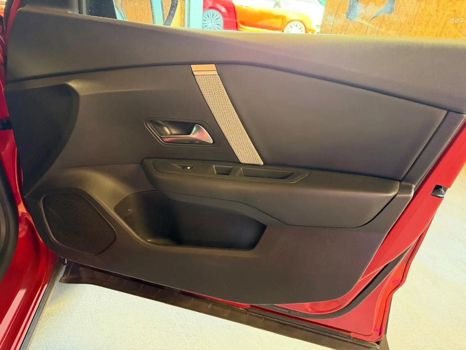 Intérieur de la porte côté gauche rouge de la Citroën C4 X 2021, avec panneau noir et poignée argentée.