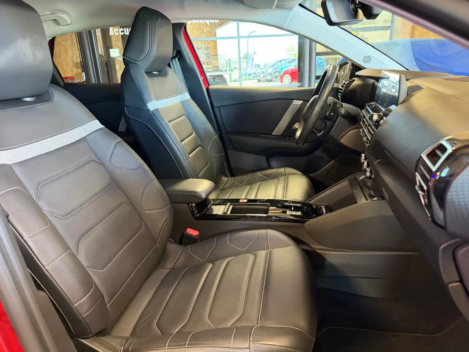 Intérieur avant du Citroën C4 X 2021 en cuir noir, vue côté gauche avec tableau de bord et console centrale visibles.