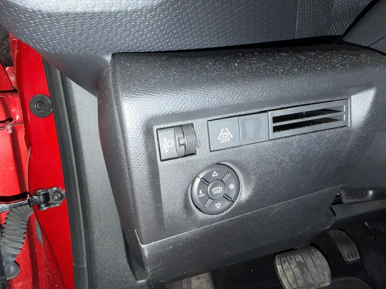 Détail du tableau de bord côté gauche noir du Citroën C4 X rouge, avec commandes d’éclairage et ventilation.