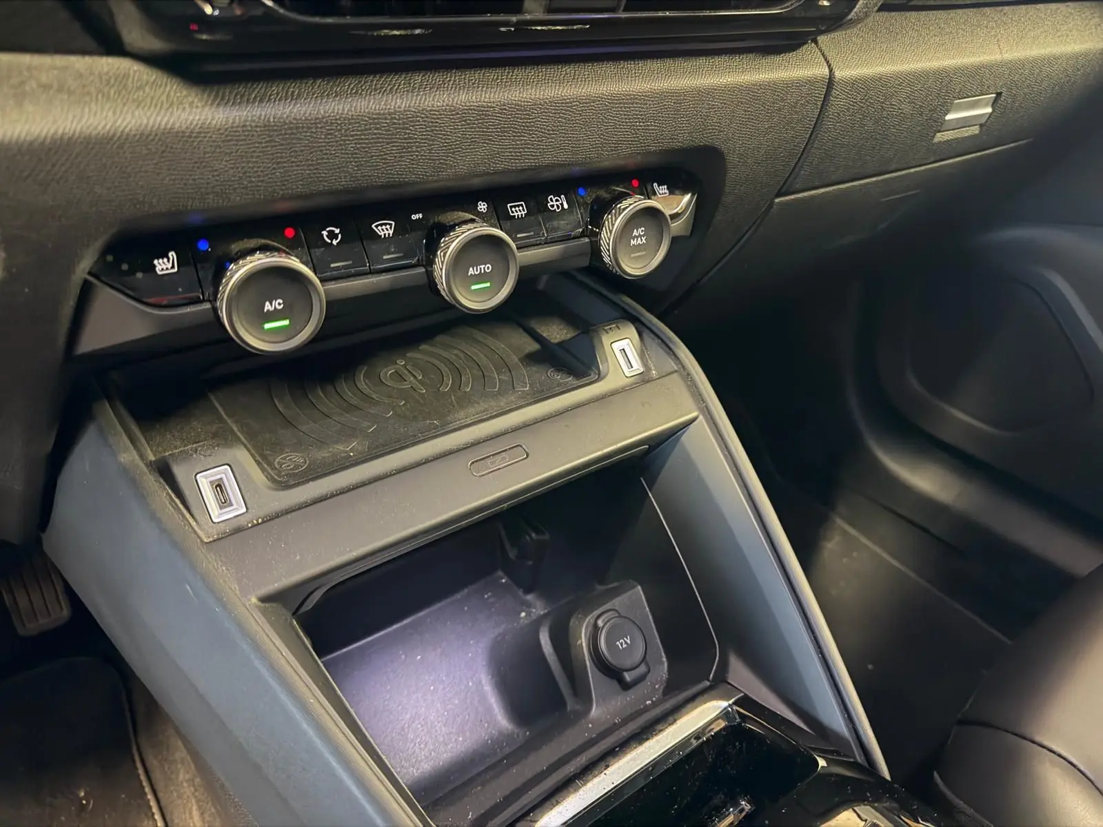 Vue rapprochée de la console centrale noire du Citroën C4 X 2021, avec commandes climatisation et prise 12V visible.