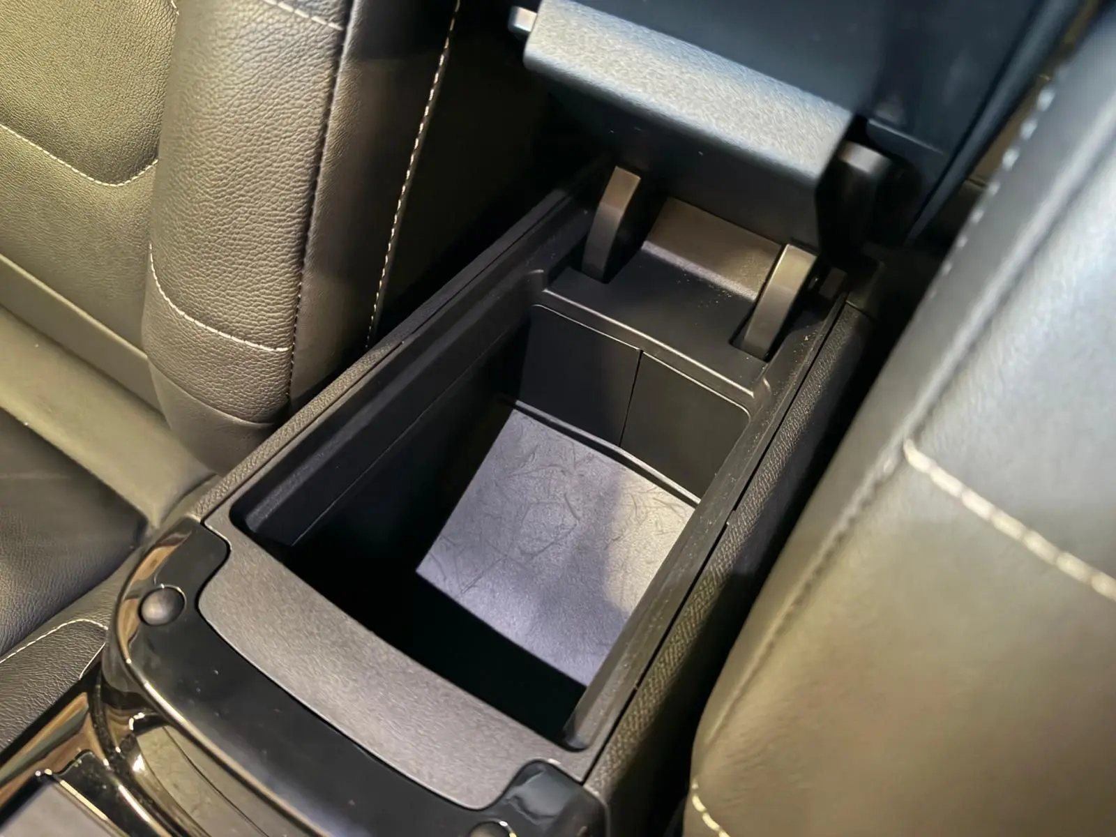 Vue rapprochée de la console centrale ouverte avec rangement intérieur en plastique noir sur Citroën C4 X 2021.