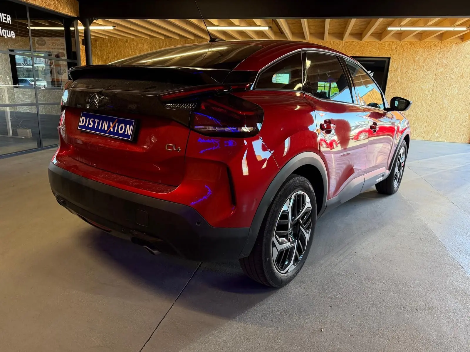 Vue 3/4 arrière droite d'une Citroën C4 X rouge métallisé avec toit noir et jantes alliage distinctives.