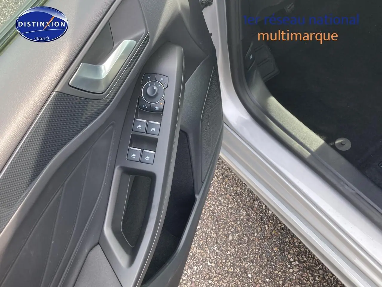 Vue rapprochée de la portière conducteur grise d'une Ford Focus 2025 avec commandes électriques des vitres et rétroviseurs.