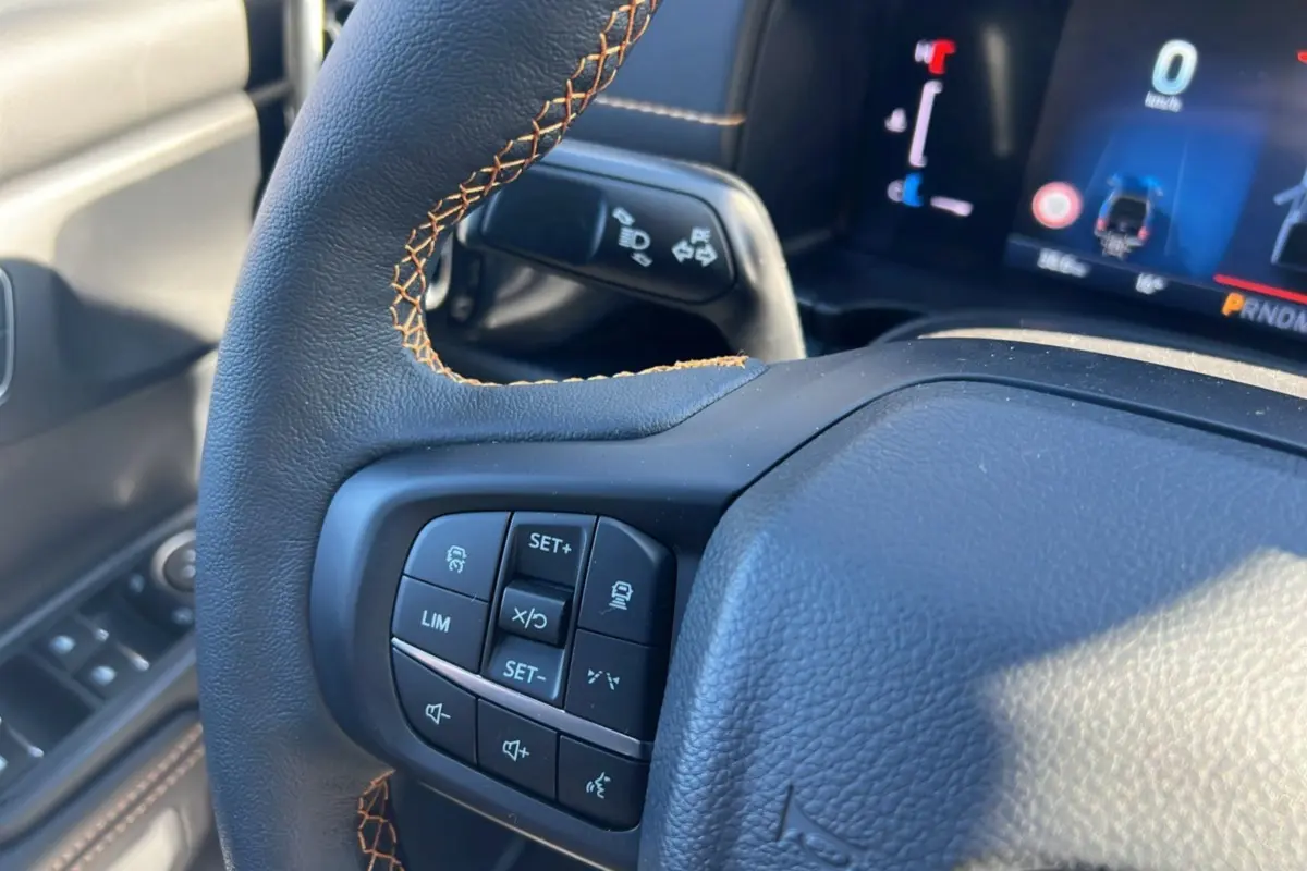 Gros plan sur le volant avec commandes multifonctions et tableau de bord numérique du Ford Ranger Wildtrak bleu lightning 2028.