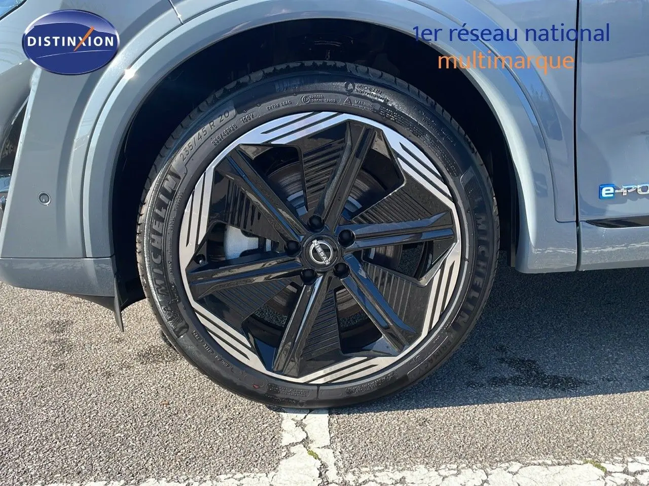 Gros plan sur la roue avant gauche du Nissan Qashqai gris céramique, jante noire et argentée au design moderne.