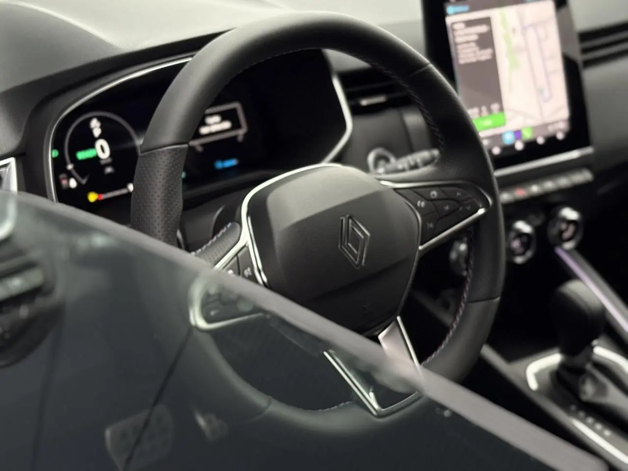 Vue rapprochée du volant multifonction noir et tableau de bord numérique de la Renault Clio hybride 2025.