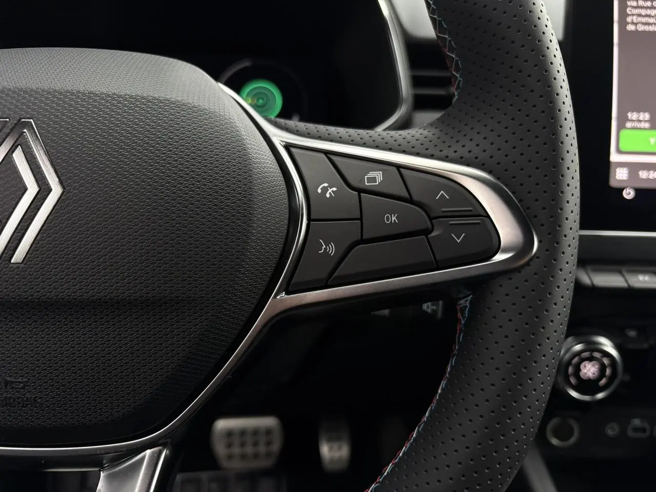 Gros plan sur le volant multifonction perforé avec surpiqûres bleues de la Renault Clio Gris Rafale 2025, version Esprit Alpine.