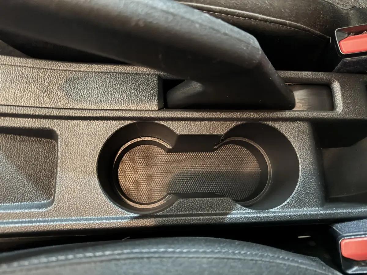 Gros plan sur les porte-gobelets noirs et le frein à main central de la Renault Clio Business E-Tech hybride 2021.