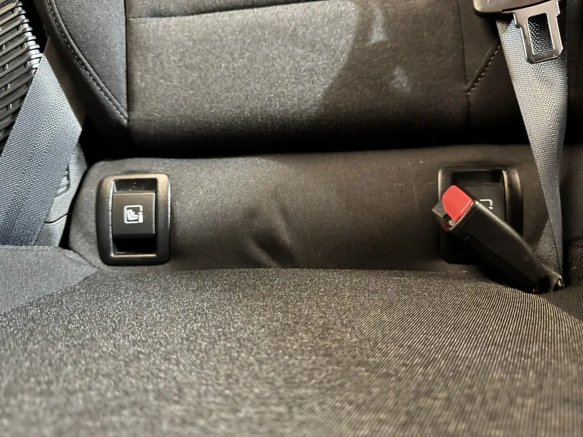 Gros plan sur la banquette arrière noire de la Renault Clio Business E-Tech hybride, montrant les boutons de rabattement et la ceinture de sécurité.