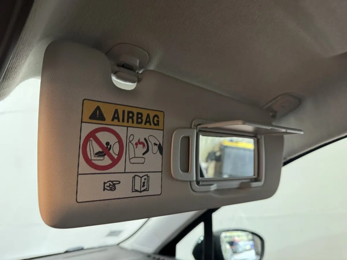 Détail intérieur du pare-soleil côté conducteur avec miroir de courtoisie et avertissement airbag dans une Renault Clio noire.
