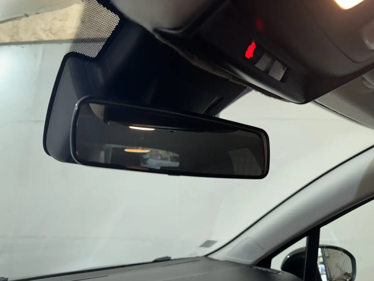 Vue intérieure centrée sur le rétroviseur intérieur d'une Renault Clio noire, avec plafond et pare-brise visibles.
