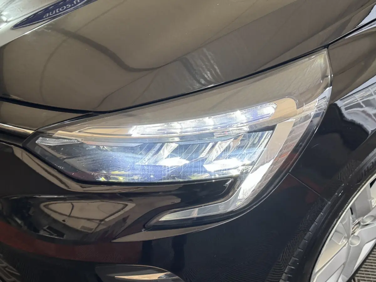Gros plan sur le phare avant droit LED d'une Renault Clio Business E-Tech hybride noire, soulignant ses lignes modernes.