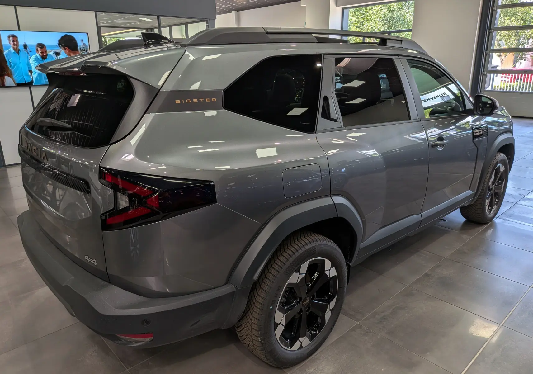 Vue 3/4 arrière droite du Dacia Bigster Hybrid-G 150 4x4 en gris schiste, avec jantes biton noires et toit noir.