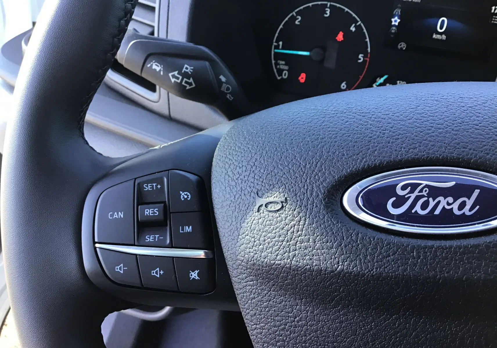 Gros plan sur le volant noir du Ford Transit Chassis Cabine 2024 avec commandes intégrées et logo Ford central.