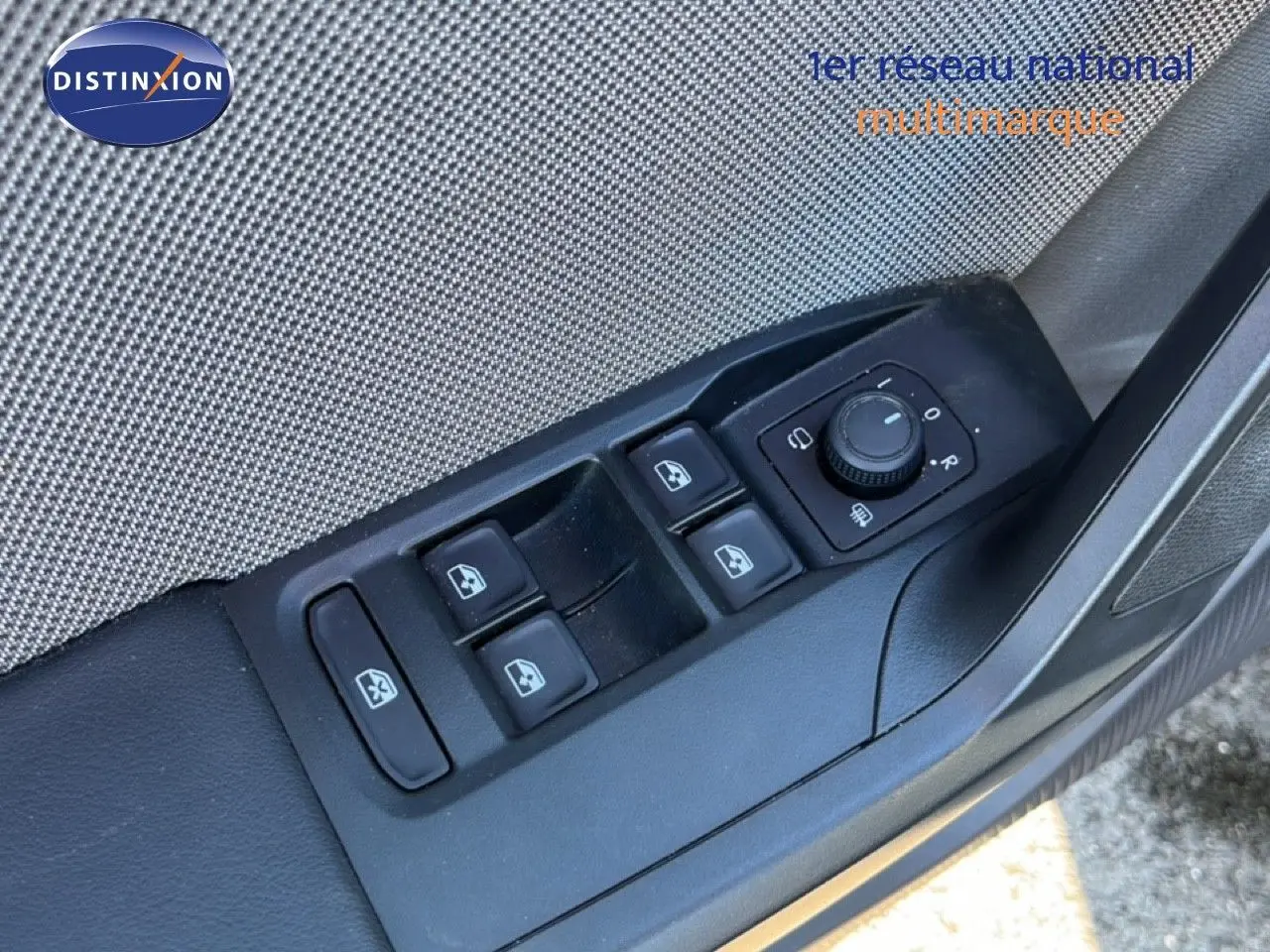 Vue rapprochée sur les commandes de lève-vitres et réglage des rétroviseurs côté conducteur d'une SEAT Leon gris magnétique.