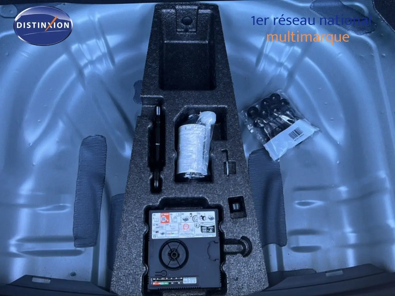 Vue plongeante sur le coffre d’un SEAT Leon gris métallique, montrant le rangement d’outils et kit de réparation.