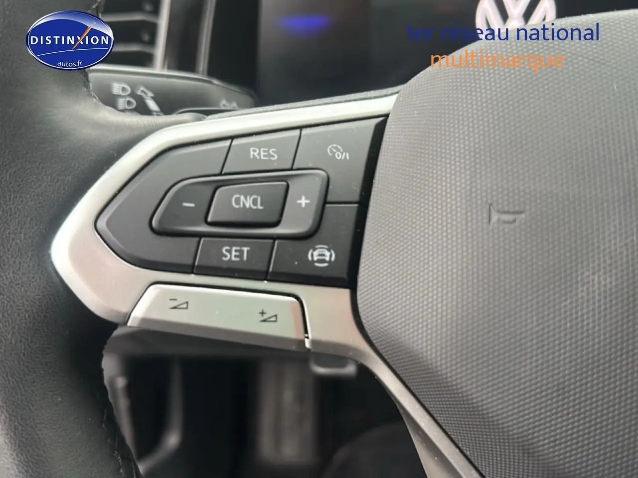 Gros plan sur les commandes au volant côté gauche d’une Volkswagen Polo gris cendre, intérieur moderne et fonctionnel.