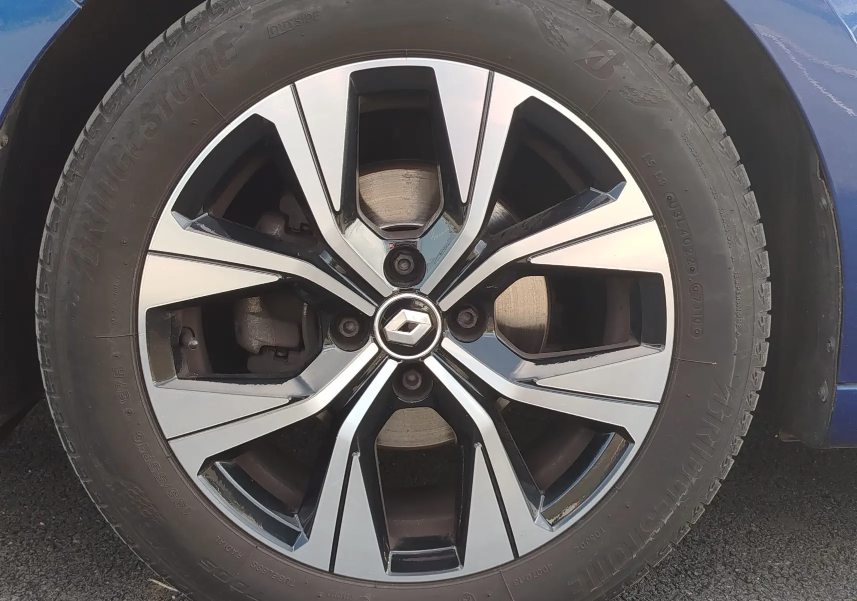 Gros plan sur la jante alliage bi-ton et pneu Bridgestone d'une Renault Clio bleu Iron, côté avant droit.