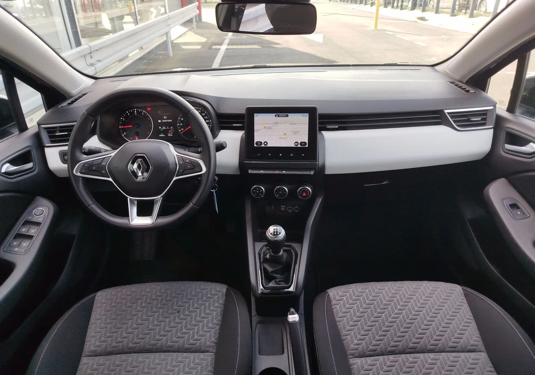 Vue intérieure avant de la Renault Clio 2022, tableau de bord avec écran tactile et volant multifonction noir.