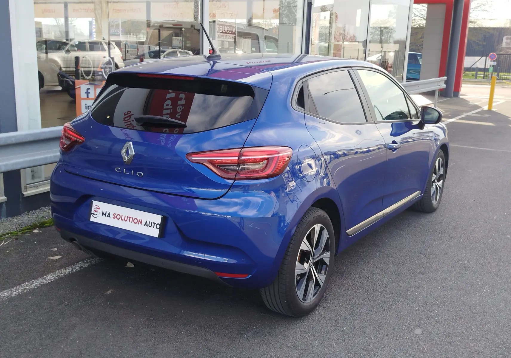 Renault Clio 1.0 SCe 65ch Evolution bleu Iron vue 3/4 arrière droit, avec vitres teintées et jantes alliage bicolores.
