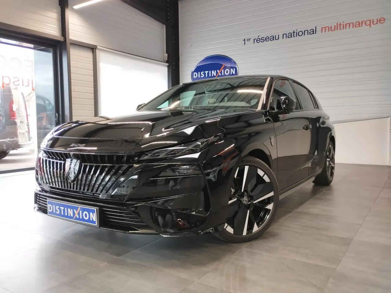 Peugeot 308 noir métal vue 3/4 avant droit en intérieur, avec calandre et jantes alliage distinctives.