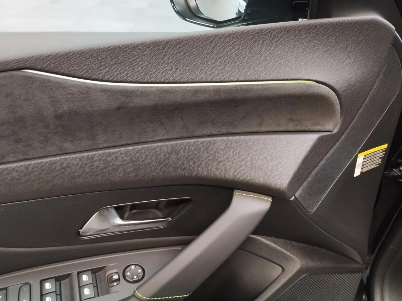 Détail de la porte avant gauche noire avec garniture en similicuir et surpiqûres vert Adamite sur Peugeot 308 Hybrid.