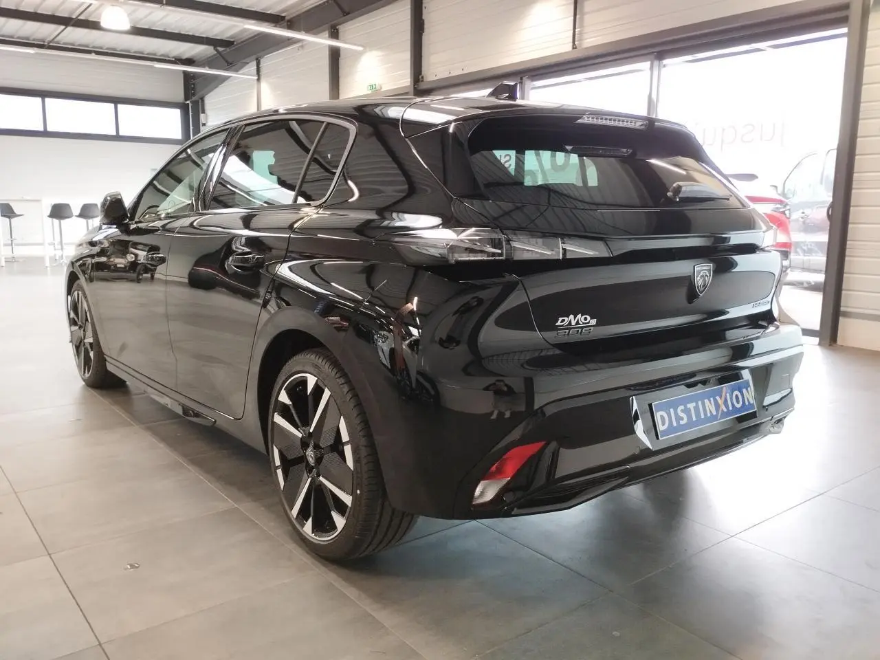 Vue 3/4 arrière droite d'une Peugeot 308 noire métallisée avec jantes alliage bi-tons et feux arrière LED griffés.