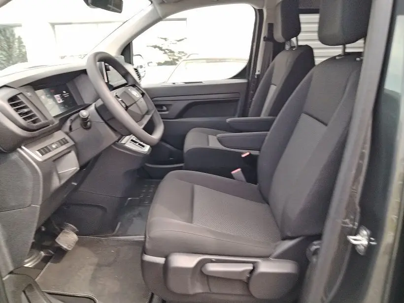 Vue intérieure côté conducteur du Citroën Jumpy Gris Titane 2025, sièges avant avec accoudoirs et volant multifonction.