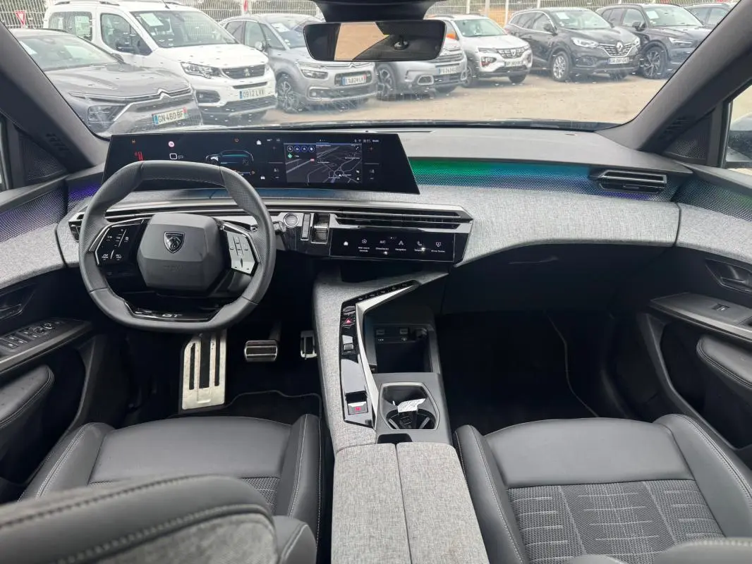 Vue intérieure avant du Peugeot 5008 Hybrid 145 ch e-DCS6 GT 2025, tableau de bord moderne avec cockpit numérique et sellerie noire.