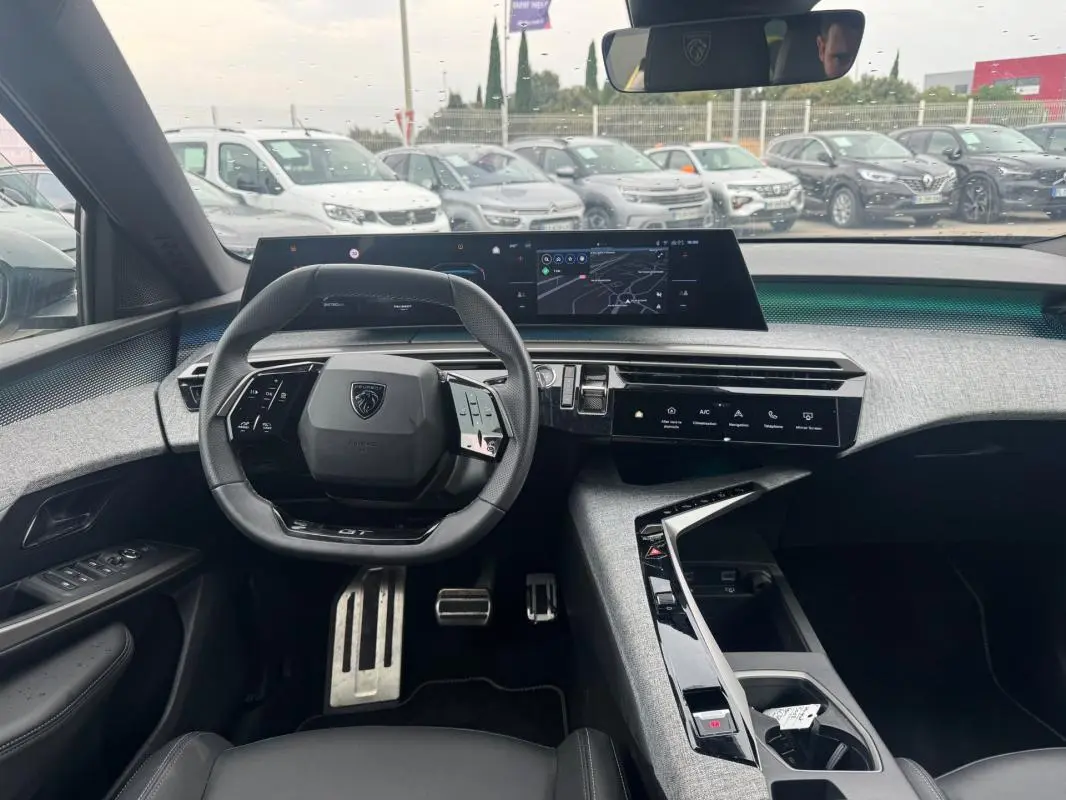 Vue intérieure du poste de conduite du Peugeot 5008 Hybrid 145 ch e-DCS6 GT 2025, avec volant compact, écran tactile large et finition noire.