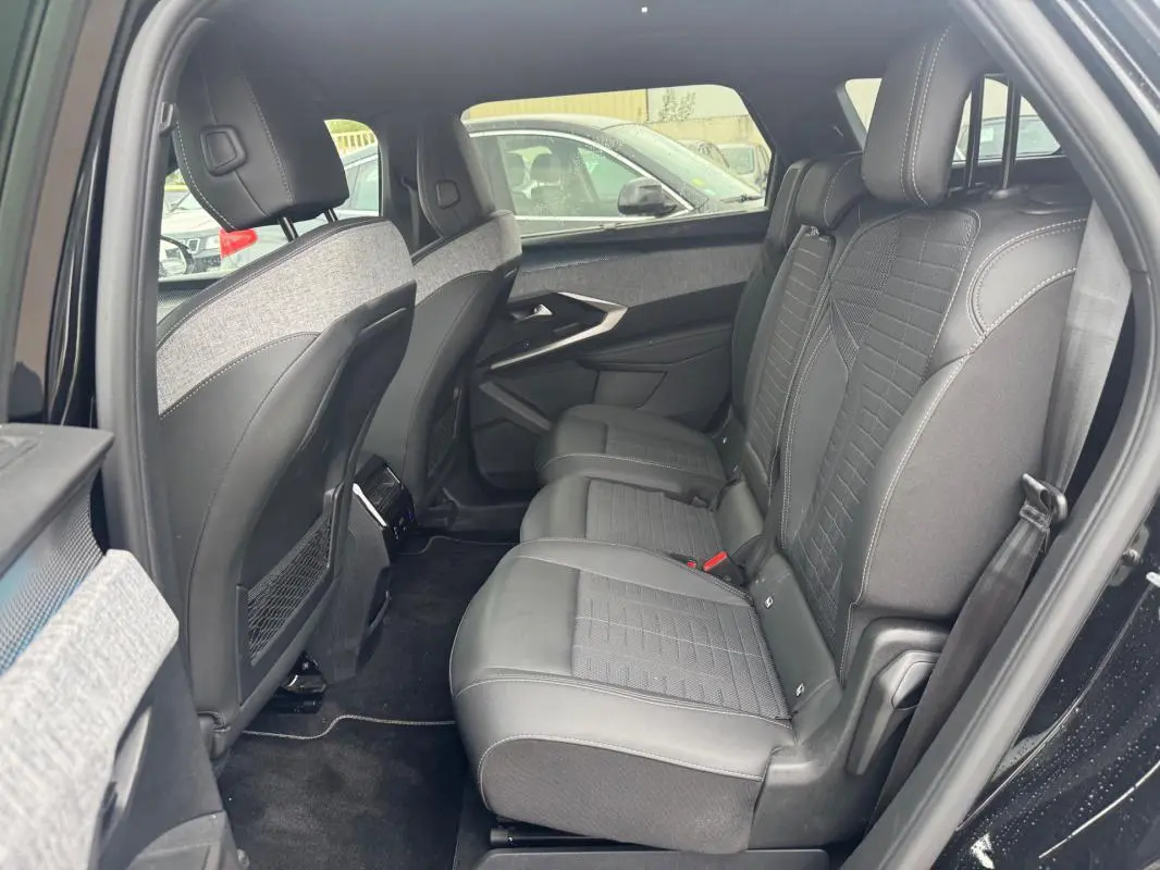 Vue intérieure côté droit des sièges arrière en cuir noir et tissu gris du Peugeot 5008 Hybrid 2025, avec porte ouverte.