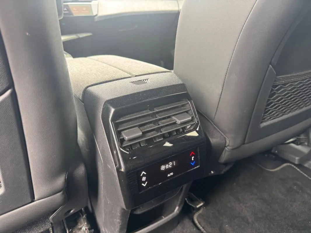 Vue rapprochée de la console centrale arrière du Peugeot 5008 noir, montrant la ventilation et le contrôle de climatisation digital.