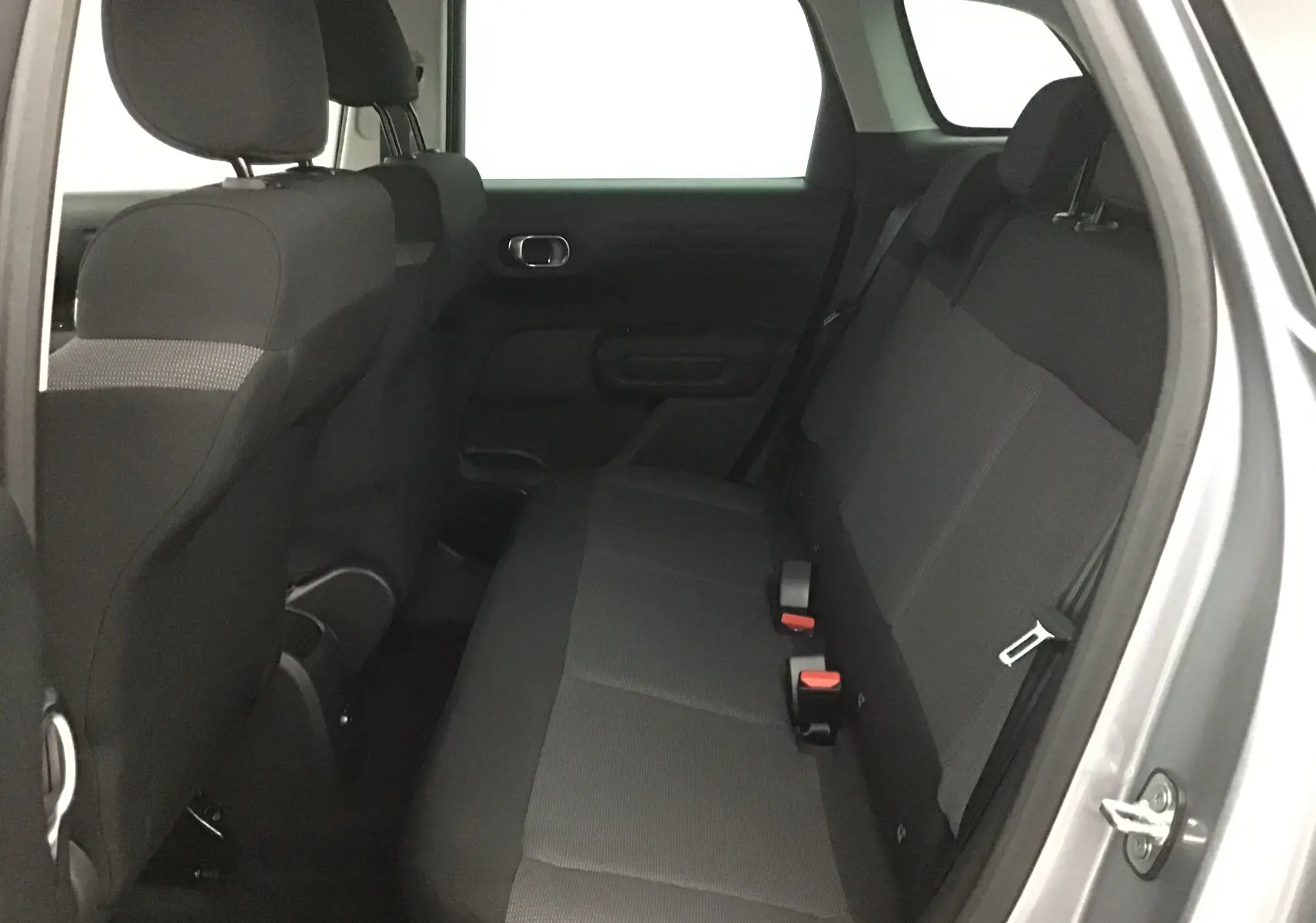 Vue intérieure côté droit des sièges arrière noirs du Citroën C3 Aircross 2024 gris platinium avec ceintures visibles.