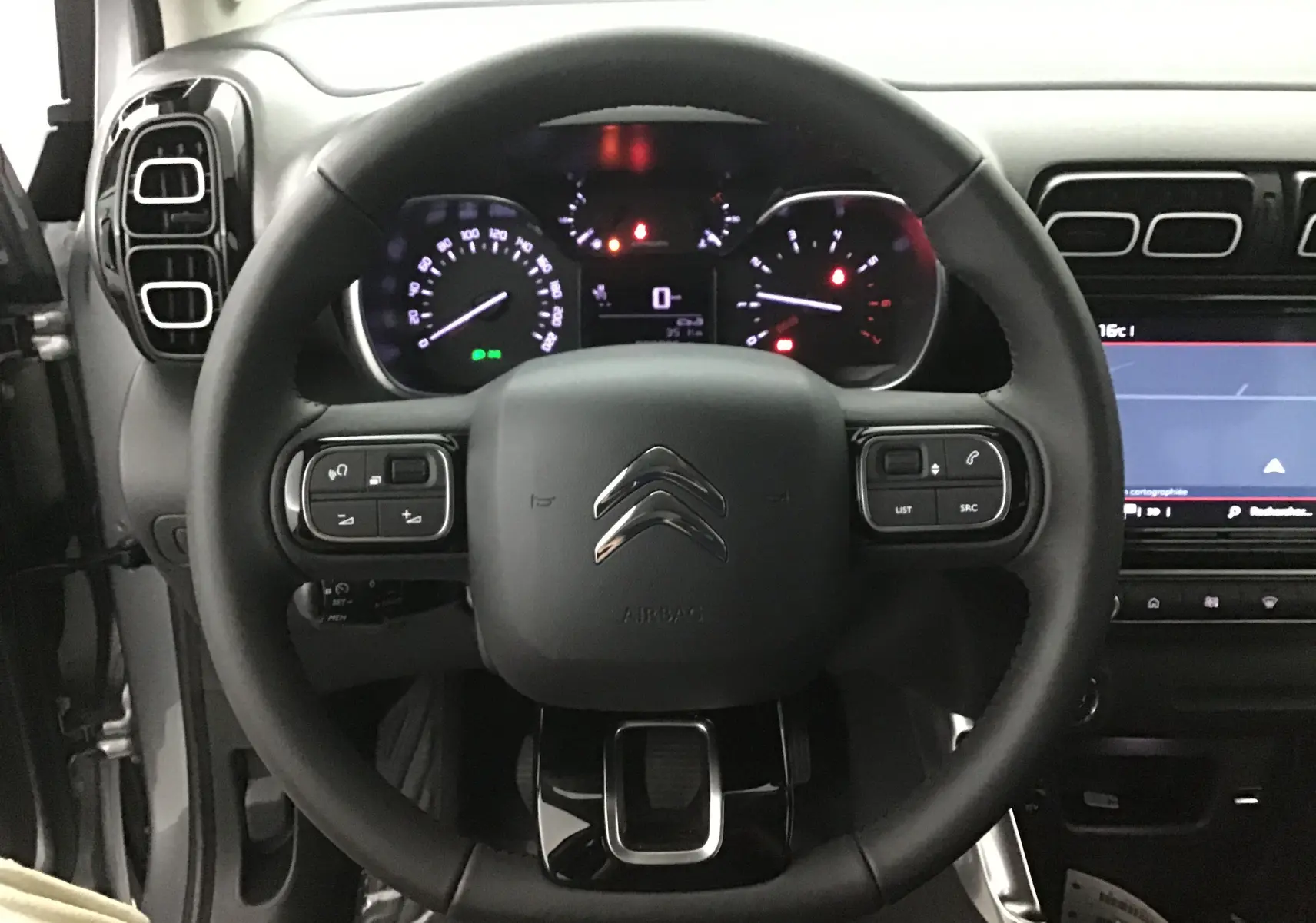 Vue intérieure centrée sur le volant noir du Citroën C3 Aircross 2024 avec tableau de bord et écran tactile visibles.
