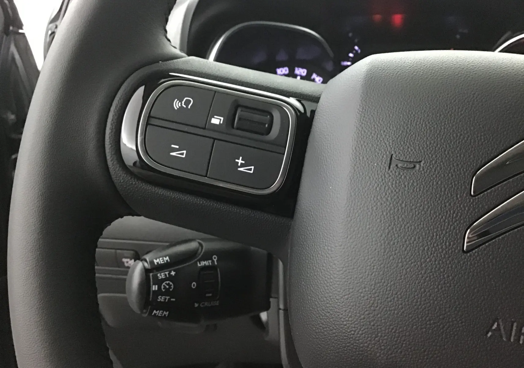 Gros plan sur le volant en cuir du Citroën C3 Aircross 2024, avec commandes audio et régulateur de vitesse visibles.