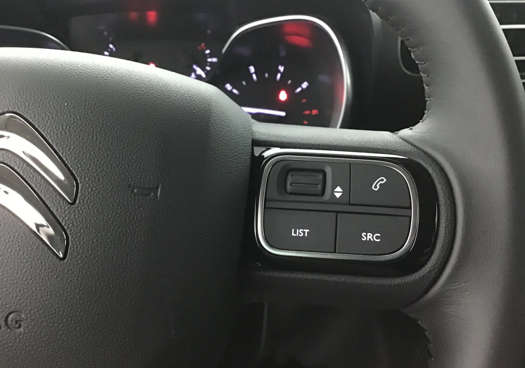 Gros plan sur les commandes à droite du volant cuir noir du Citroën C3 Aircross 2024, avec logo chromé visible.