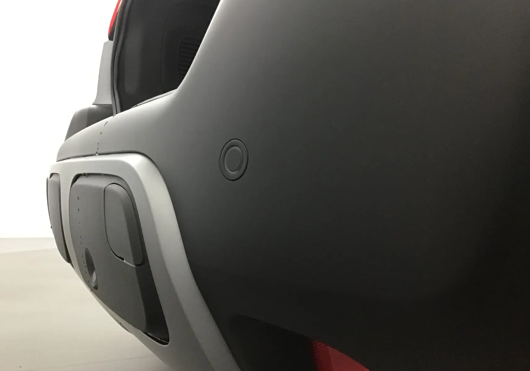 Gros plan sur le pare-chocs arrière gris platinium et noir du Citroën C3 Aircross 2024 avec capteur de recul visible.