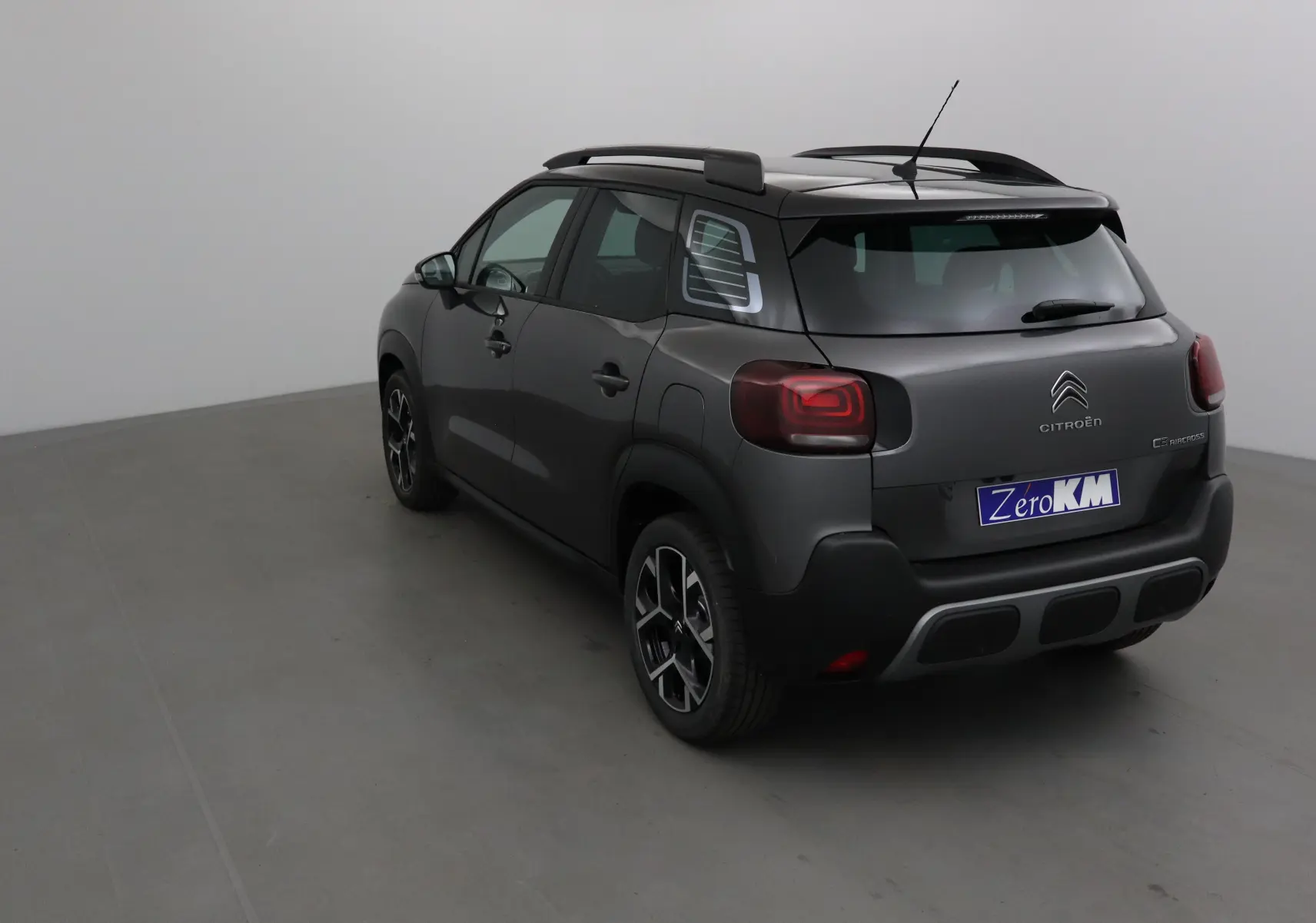 Vue 3/4 arrière droite d'un Citroën C3 Aircross gris platinium et noir avec barres de toit et feux arrière LED.
